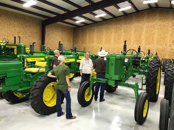 Hired Hand customers Teresa Sparger, Red McCombs Ranch and Kaitlyn Moss, Moss Longhorns admiring Lynn&#39;s John Deere tractor collection. 
